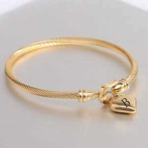 Detailed macro of 18K gold cable bracelet with heart pendant and B letter engraving