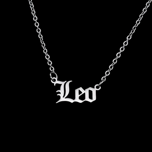 Macro detail of silver stainless steel Leo zodiac necklace with gothic font pendant