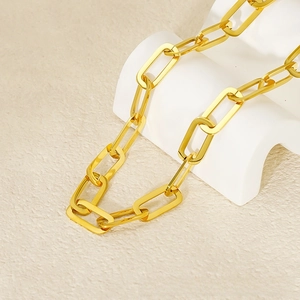 Close-up of a gold paperclip chain necklace with a high-polished finish on a white stand