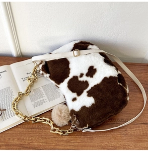 Detail of cow print faux fur tote with leather strap and decorative gold chain
