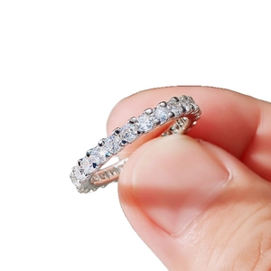 Elegant silver eternity ring with sparkling zircon stones held by a hand on white background