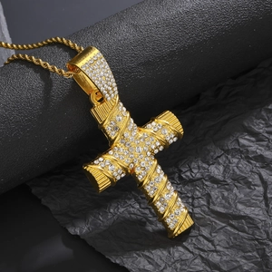 Macro shot of gold cross pendant with sparkling rhinestones on a twist chain detail