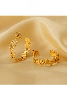 Close-up of gold hollow star earrings made of titanium steel on silk fabric