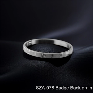 Detail of silver titanium steel bangle with engraved badge and Greek key pattern