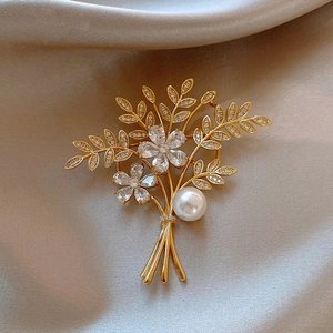 Elegant gold flower brooch with sparkling zircons and a white pearl on satin