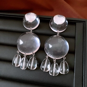 Macro view of transparent resin round earrings with multi-layered droplet pendants
