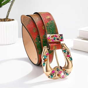 Detail of western brown leather belt with embossed floral patterns and rhinestone buckle
