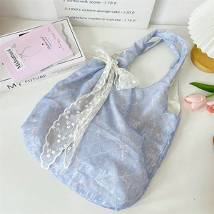 Détail du sac cabas en mesh bleu clair avec motif nœud rose et grand nœud en dentelle blanche