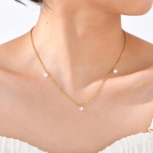 Close-up of a gold chain necklace featuring three sparkling round zircon crystal pendants