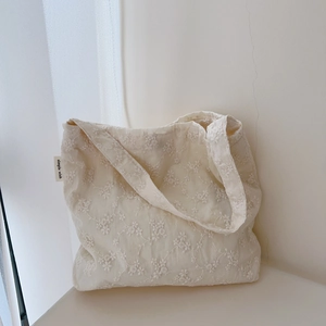 Detail of floral embroidery on ivory cotton tote bag with a woven simple wish label