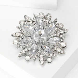 Detailed macro of a crystal flower brooch with marquise stones on a white platform