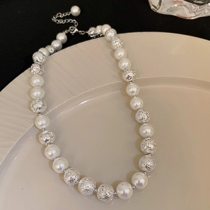 Detail of silver textured beads and faux pearls on a minimalist layered necklace