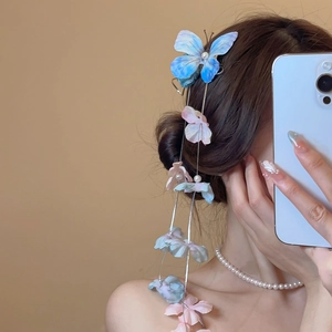 Detailed close-up of blue butterfly hair clip with floral tassels and pearls worn on hair