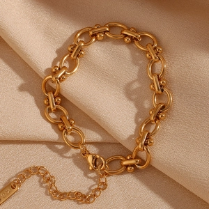 Détail d'un bracelet gourmette doré 18 carats avec fermoir homard sur du satin