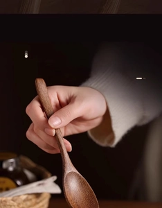 Detailed view of hand-held natural wood spoon showing unique grain and solid texture