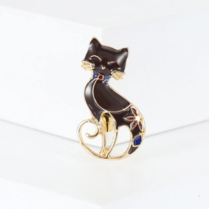 Close-up of a black enamel cat brooch with gold metal trim and colorful accents