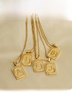 Détail de pendentifs rectangulaires en acier inoxydable plaqué or 18 carats sur soie