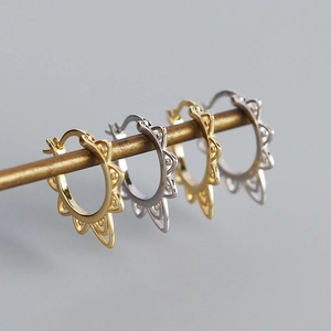 Macro shot of gold and silver sunflower pattern hoop earrings on a metal rod