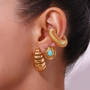Macro shot of gold plated hollow teardrop earrings and turquoise ear cuff jewelry set