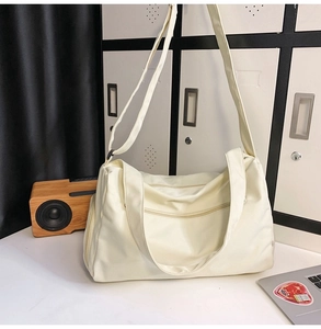 Détail d'un sac de sport beige en nylon à grande capacité avec plusieurs fermetures éclair
