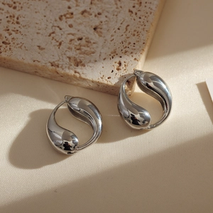 Macro detail of silver teardrop hoop earrings with polished finish on stone background