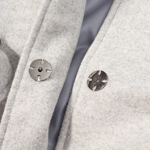 Détail d'un manteau en laine gris clair avec boutons-pression en métal argenté