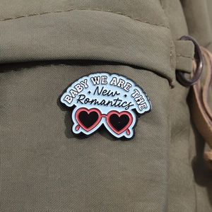 Detailed view of pink heart sunglasses enamel pin on olive green fabric bag