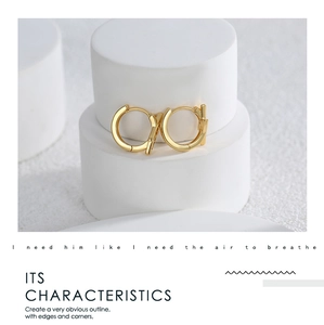 Detail of golden geometric hoop earring with zircon lightning bolt on a white pedestal