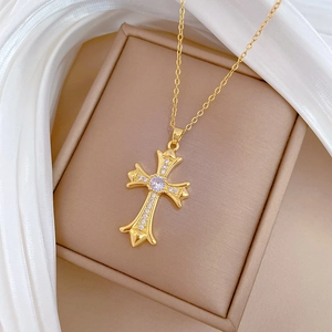 Macro shot of gold cross necklace with shimmering cubic zirconia on beige silk background