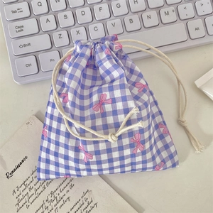 Close-up of purple gingham drawstring pouch with pink bow prints on a desk setup
