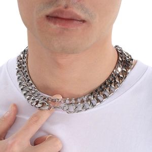 Close-up of layered silver Cuban link chains on a model with polished stainless steel texture