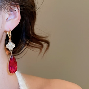 Macro detail of gold flower drop earring featuring red pear-cut stone and pavé zircon