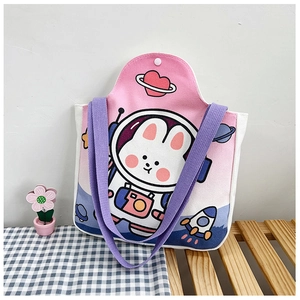 Close-up of canvas tote bag with astronaut bunny illustration on a wooden bench