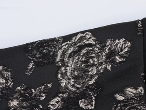 Close-up of black jacquard fabric featuring shiny silver rose floral patterns for a dress