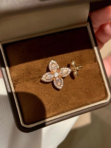 Close-up of golden four-petal flower brooch with sparkling rhinestones on velvet box