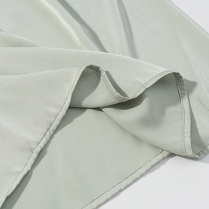 Detail des hellgrünen Neckholder-Maxikleides mit Seidentextur und feiner Saumverarbeitung