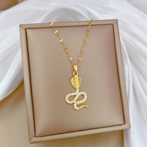 Elegant gold snake necklace with sparkling crystals on white silk background