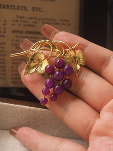 Macro shot of vintage grape brooch with golden leaves and vibrant purple gemstone clusters
