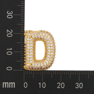 Macro detail of gold-plated letter D pendant with cubic zirconia inlay and scale measure