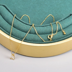 Detailed close-up of 18K gold chain with lobster clasp and teardrop zircon pendant