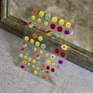 Transparent nail stickers featuring colorful smileys and sun patterns on a wooden frame