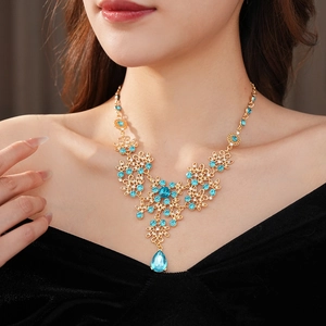Macro shot of gold vintage flower necklace with blue stones and tassel worn by a model