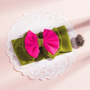 Close-up of olive green baby headband with magenta waffle texture bow on lace paper