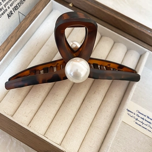 Detail of tortoiseshell acrylic hair claw with large pearls in a wooden gift box