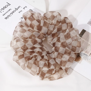 Detail shot of a large brown and white checkered organza scrunchie with airy mesh texture