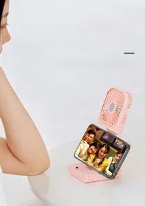 Pink portable fan folded as a phone stand for desk use showing versatile functionality