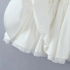 Macro detail of white french ballet style dress featuring woven fabric and lace trim edge
