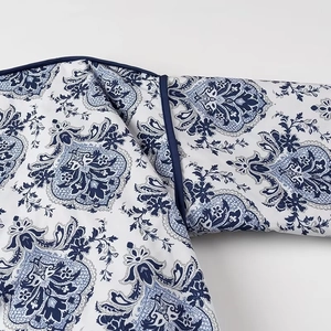 Close-up of blue and white floral damask pattern fabric with dark navy binding on the edge