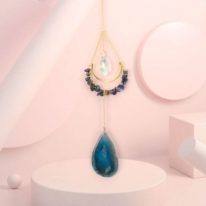 Close-up of agate slice and crystal crescent moon suncatcher on pink geometric stands