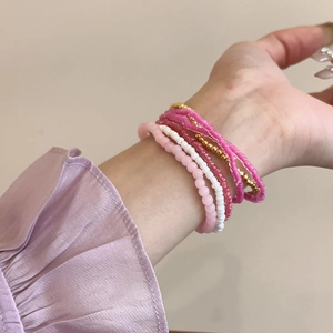 Detail of bohemian multilayer beaded bracelet set with pink and gold accents on wrist